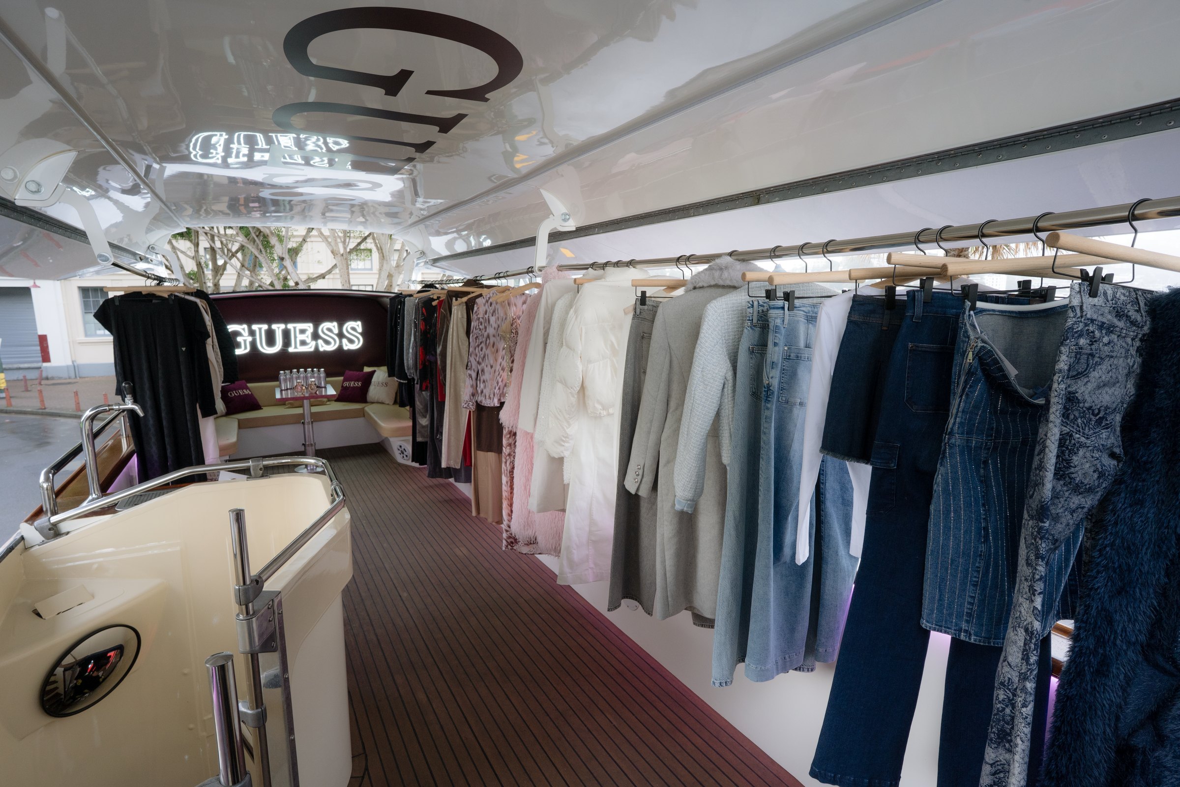 GUESS clothing collection displayed on rails inside the bus
