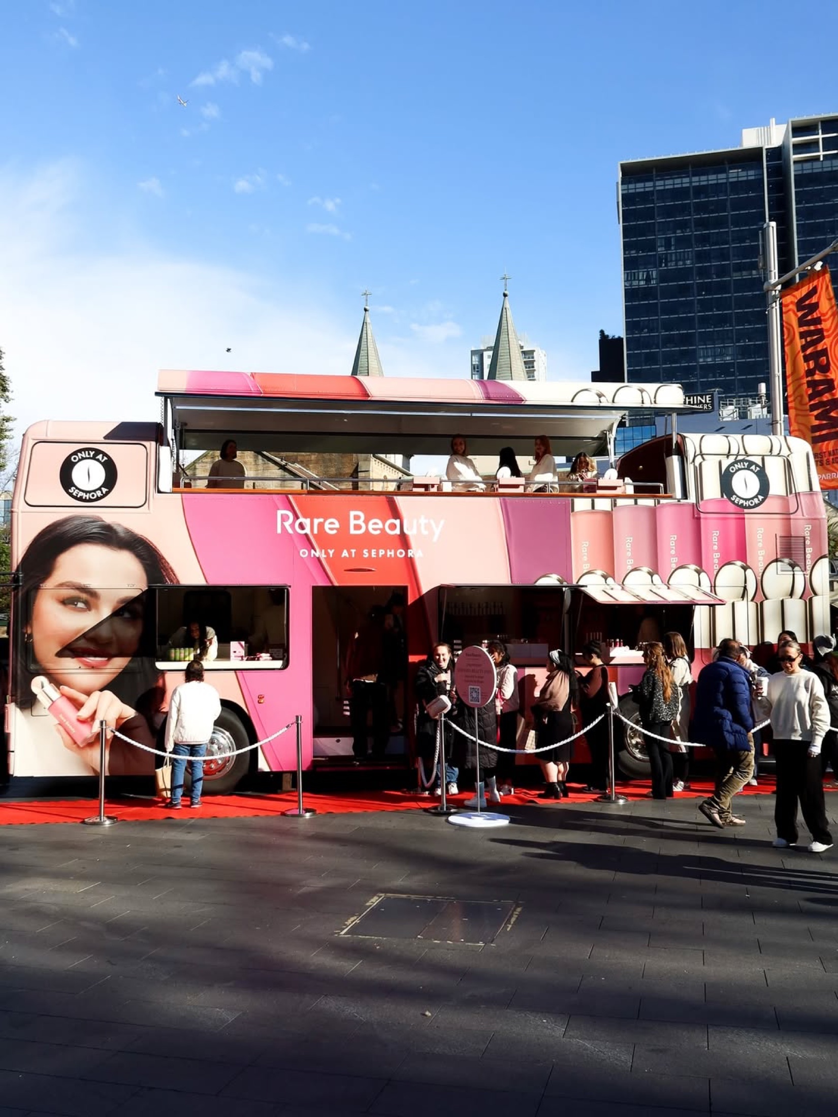 A crowd gathering around the Rare Beauty Blush Bus
